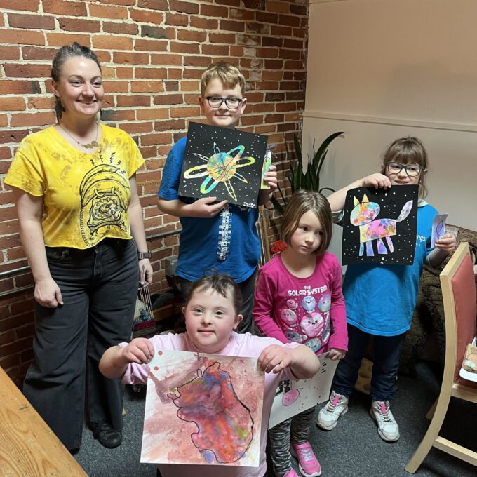 picture of 4 children and adult woman holding artwork.
