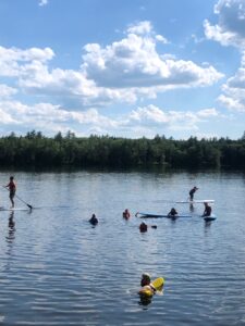 people in a lake floating and using paddle boards